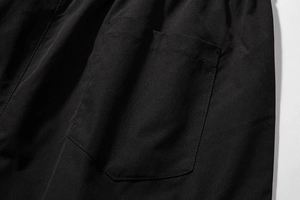 Detailed close-up of the stitching and fabric on the black cargo shorts side pocket