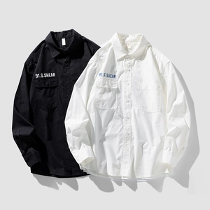 Flat lay of black and white long sleeve button-up shirts with chest pockets and 91.S.SHEAR text