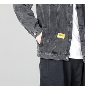 Detail of dark gray washed denim jacket featuring metallic buttons and yellow woven label
