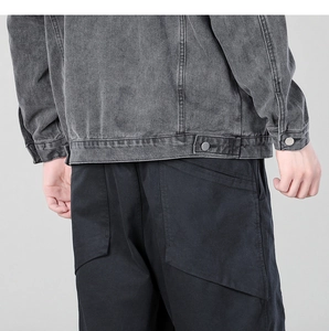 Detail view of charcoal grey washed denim jacket back hem and cargo pants pocket