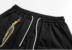 Detail of black sports shorts featuring elastic waistband, white drawstring and woven charm