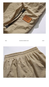 Detailed view of khaki cargo shorts showing elastic waistband and leather logo patch