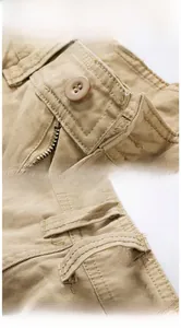 Detail of khaki cargo shorts featuring resin button, metal zipper, and reinforced stitching
