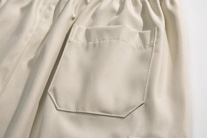 Macro detail of the beige cargo shorts featuring elastic waistband and functional patch pocket