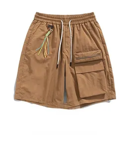 Detail of brown cargo shorts with elastic drawstring waist and multi-pocket utility design