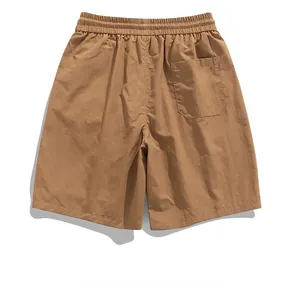 Detailed view of elastic waistband and rear utility pocket on brown cargo shorts