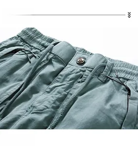 Detail of elastic waist with drawstring and vintage metal button on blue cargo pants