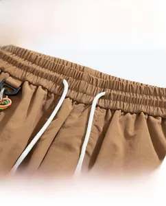 Detail of waist drawstring and plastic hook on brown ice silk cargo shorts