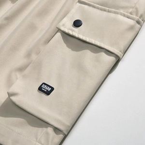 Close-up of khaki cargo shorts pocket with snap button and designer rubber patch