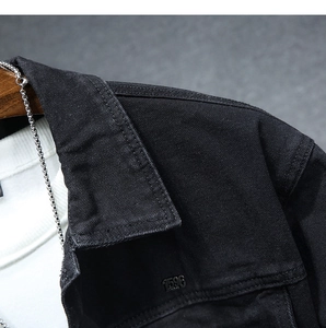 Dettaglio colletto giacca denim nero con targhetta metallo 1596 e catena argento