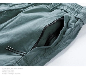 Detail of sage green cargo shorts with elastic waist, drawstring, and zipper pockets