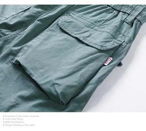 Detail of green cargo shorts featuring double-stitched flap pockets and cotton fabric