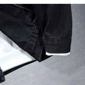 Dettaglio ravvicinato di una giacca di jeans nera con trama saia e fodera a coste