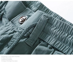 Detail of grey-green cargo shorts featuring elastic drawstring waist and button closure