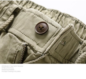 Detail of army green cargo pants featuring elastic waist, button, and durable metal zipper