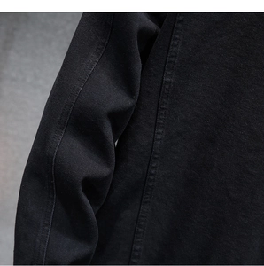Dettaglio giacca in denim nero con doppie cuciture rinforzate e trama in twill