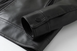Detail of premium black PU leather jacket showing sleeve snap button and fine stitching