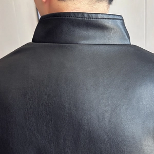Detailed macro shot showing the black PU leather texture and collar stitching of the jacket