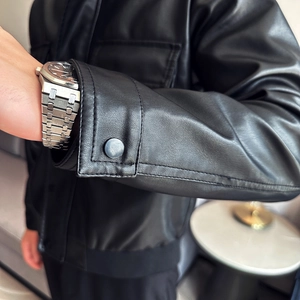 Detailed close-up of the black PU leather jacket sleeve with a metallic snap button