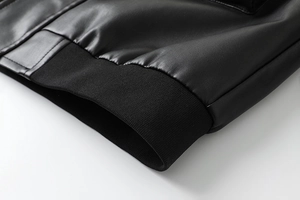 Close-up of black PU leather jacket featuring ribbed knitted hem and fine texture