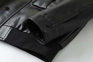 Close-up of black PU leather jacket showing ribbed hem and snap button cuffs