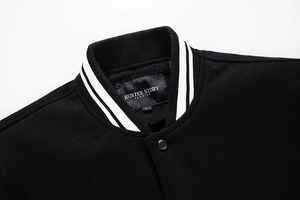 Detail of black baseball jacket collar with black and white striped ribbed texture and snaps