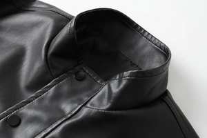 Detail of black faux leather jacket collar with stand-up style and matte metal snap button