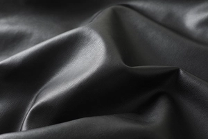 Close-up of premium black PU leather texture with detailed lychee grain and soft sheen