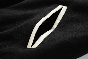 Close-up of black woolen jacket pocket with off-white leather piping detail and texture