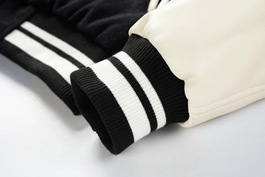 Detail of contrast PU leather sleeve and striped rib-knit cuffs on baseball jacket