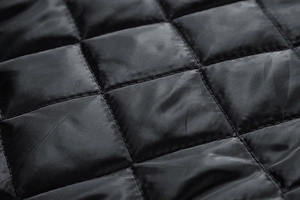 Detailed macro view of black quilted fabric with square pattern and satin luster