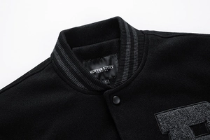 Detail of striped rib-knit collar and brand label on black wool varsity jacket