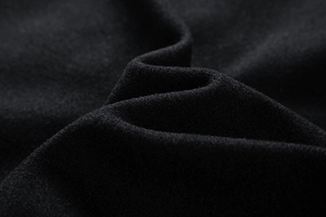 Close-up detail of premium thick black wool fabric on a varsity jacket showing fine texture