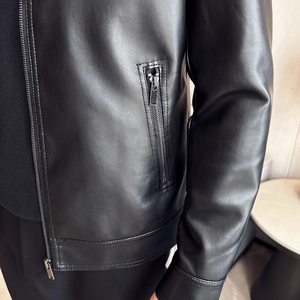 Close-up of black PU leather jacket showing lychee grain texture and metal zipper detail