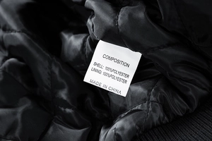 Detail view of the interior care label and quilted lining on a black baseball jacket