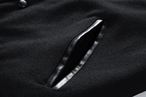 Detail of wool blend jacket featuring leather-trimmed slant pocket and metallic button