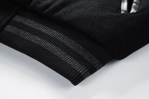 Close-up of black wool jacket cuff with grey striped ribbed knit and leather trim detail