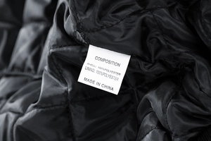 Macro shot of product care label on black quilted lining of the polyester jacket