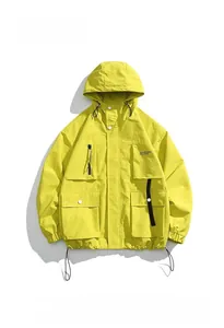Detail of yellow waterproof outdoor jacket featuring large cargo pockets and black chest strap