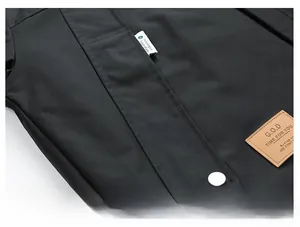 Detail of waterproof black jacket featuring a large flap pocket with a silver metal button