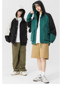Detail of outdoor windbreakers with color-block design, hoods, and large utility pockets