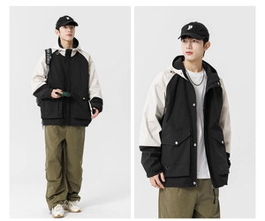 Detail view of hooded color-block outdoor jacket with metal snaps and utility pockets