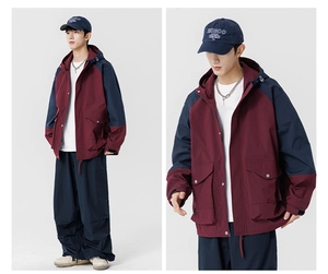 Detail view of burgundy and navy outdoor cargo jacket with adjustable hood and large pockets