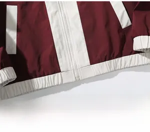Detail view of burgundy sport jacket with white elastic hem and durable zipper