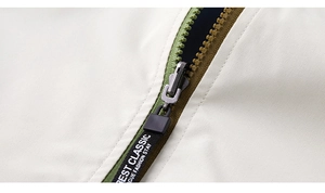 Detail of metal zipper with branded puller on beige and olive green casual jacket