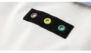 Detailed macro view of colorful metal eyelets on a black fabric patch on casual jacket