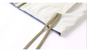 Detail of jacket hem with blue lining, beige drawstrings and premium green zipper teeth