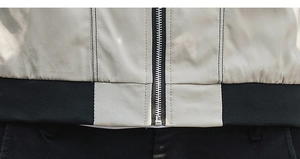 Detail of metal zipper and black ribbed hem on a minimalist slim fit casual jacket