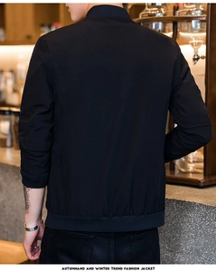 Detail of windproof black varsity jacket with ribbed collar and cuffs in cafe setting