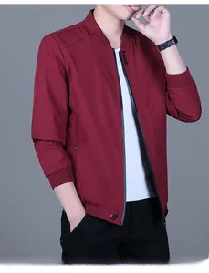 Close-up detail of dark red windbreaker jacket with ribbed collar and zipper pocket